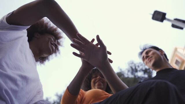 Happy multiethnic friends stacking hands for success