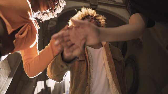 Happy multiethnic friends stacking hands for success