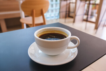 Closeup image of a white cup of hot coffee on the table in cafe