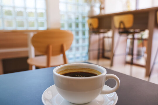 Closeup image of a white cup of hot coffee on the table in cafe