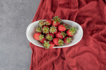 Bowl of strawberries on napkin, Fresh strawberries in plate on table, Heap of fresh strawberries in ceramic bowl, Top view fresh strawberry in wrought plate on concrete board, Fresh juicy strawberry.