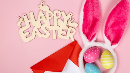 colored easter eggs and rabbit ears and envelope and blank for text on pink background easter minimal flat lay top view