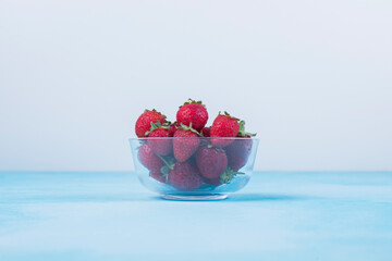 Fresh ripe organic strawberry in a white bowl on a dark slate, stone or concrete background. Top view with copy space, Strawberries in bowl on a table. Bowl filled with juicy fresh rip red strawberrie