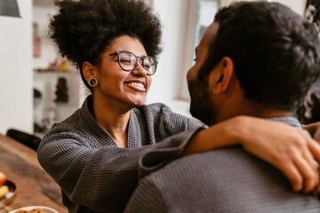 Cheerful couple hugging while spending time together at home