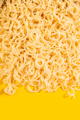 Texture of curly noodles on yellow background.