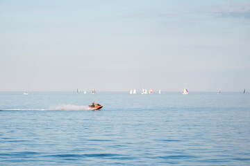 Man riding water motorcycle on Lake Ontario. Sunny day, many yachts and sailboays in the background out of focus. Summer sports and activities concept. Space for copy.