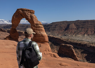 Fototapeta na wymiar A guy looks at the famous delicate arch in the Arches National Park in Moab