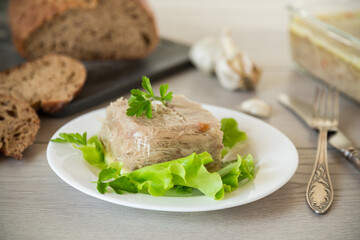 Boiled chicken meat aspic in meat gelatin broth in a plate