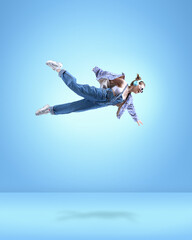 Stylish young girl in casual clothes, in headphones, flying over blue background. Creative ideas...