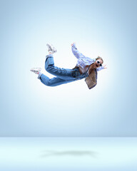Stylish young girl in casual clothes, headphones and sunglasses, flying over blue background....