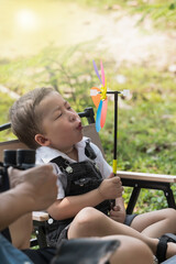 Young Asian boy blowing colorful windmill toy in park, Family Holiday