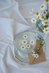 Cup of tea with chamomile flowers on a white background