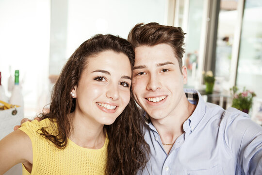Portrait of a young smiling in love couple taking a selfie. Boyfriend with girlfriend looking at the camera and take a photo together.