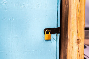  brass padlock securing a black metal hasp on a blue door room for text