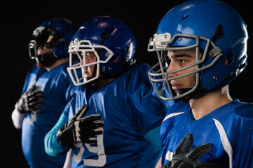 Portrait of three men in blue uniforms for American football with a hand on his chest on a black background.