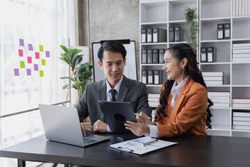 Two employees working at table in a modern office, Asian man and a woman work at office desk, Business campaign result and project planning concept, financial planning,  
