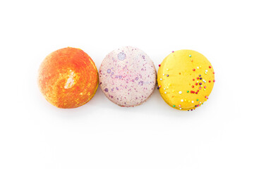 Sweet colorful yummy macarons isolated on white background. Brightly colored stacked macaroons. Three multi-colored orange, pink and yellow macaroons. French pastry made from egg whites.
