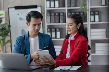 Two employees working at table in a modern office, Asian man and a woman work at office desk, Business campaign result and project planning concept.  
