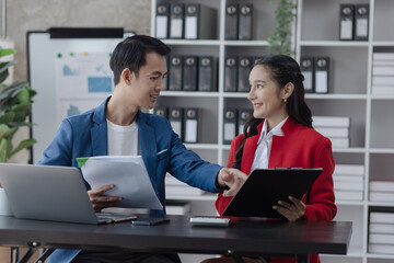 Two employees working at table in a modern office, Asian man and a woman work at office desk, Business campaign result and project planning concept.  