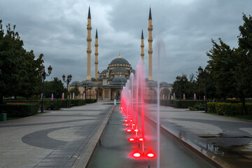 Fototapeta na wymiar Alley of red fountains against the background of the Heart of Chechnya mosque on a cloudy September evening. Grozny, Chechen Republic. Russia