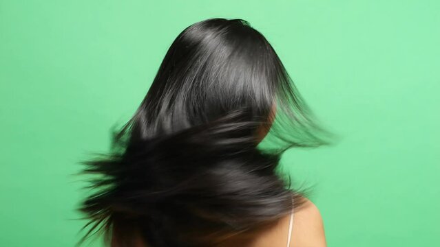 Close Up Back View Of A Woman Shaking Her Head Showing Her Long Black And Blond Straight Healthy Hair In The Green Screen Background Studio
