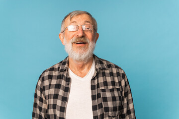 Obraz premium Portrait retired old man with white hair and beard laughter excited over blue color background