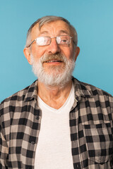 Obraz premium Portrait retired old man with white hair and beard laughter excited over blue color background