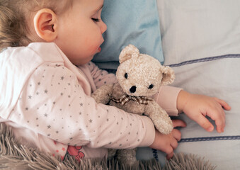Cute little girl sleeping and hugging teddy bear. Top view.