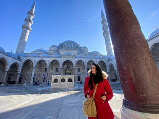 ragazza con il cappotto rosso passeggia di fronte una moschea a Istambul