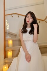 階段に座りポーズをとる白いドレスを着た若く美しい女性	