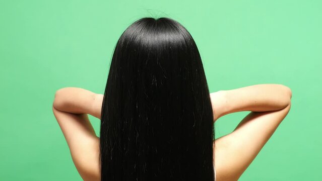 Close Up Back View Of A Woman Fluttering Her Long Black And Blond Straight Healthy Hair In The Green Screen Background Studio
