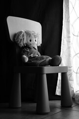 Fototapeta na wymiar Bambola triste e solitaria seduta davanti alla finestra