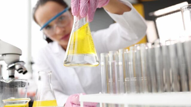 Chemist technologist pouring motor oil into flask and onto car piston in laboratory 4k movie slow motion. Quality control of machine oils concept