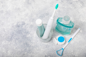 Bathroom with sonic electric toothbrush, toothpaste, mouthwash, dental floss and tongue cleaner against a blue wall. Oral hygiene. Dental care.Dentistry concept.Place for text.Place for copy.MOCKUP