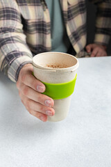 A hand holding a green cup of hot chocolate