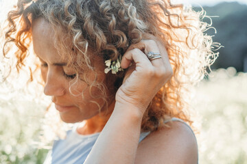 Close up portrait of mature young woman enjoying leisure outdoor in the nature in bright sun light...