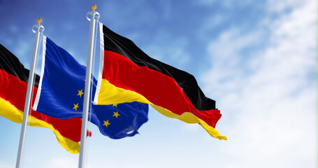 The flags of Germany and the European Union waving together on a clear day.