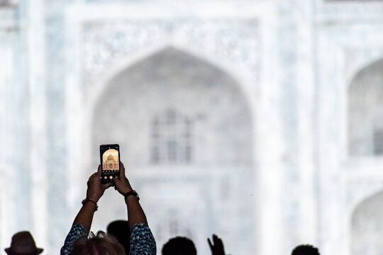 Tourists taking pictures with their mobile phones of the Taj Mahal.