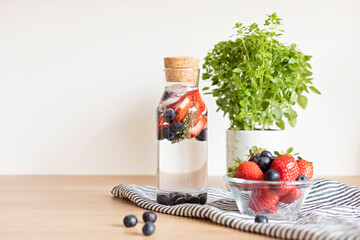 Infused  water with strawberry and blueberries in glass bottle on wooden table. Diet, detox, healthy eating, weight loss concept