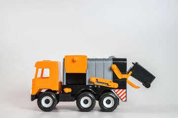 Multi-colored plastic children's toy cars on a white background. Orange garbage truck.