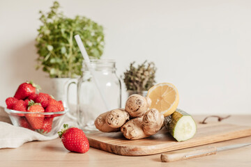 Preparation of infused  water with cucumber, lemon and ginger in glass jar on wooden table. Diet, detox, healthy eating, weight loss concept