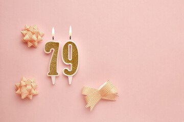 Candles with the number 79 on a pastel pink background with festive decor. Happy birthday candles. The concept of celebrating a birthday, anniversary, important date, holiday. Copy space. banner