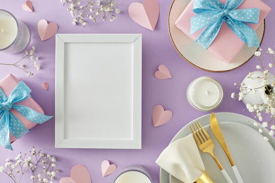 Table setting for Mother’s day idea. Top view photo of plate with cutlery gift boxes candles gypsophila flowers and hearts on lilac background. Flat lay with empty photo frame for text or advert