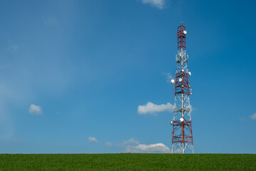 Communication tower on green  field against blue sky