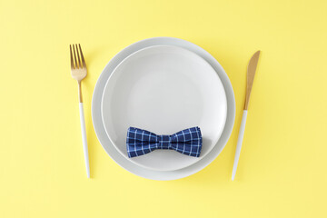 Happy Father's Day concept. Top view flat lay of white plate cutlery knife fork and trendy bow tie...