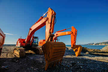 Excavators working on earthmoving at construction of new embankment