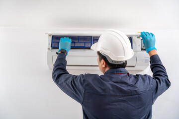 Air technician service checking and repairing air conditioner on white wall. Service concept of an air conditioner technician.