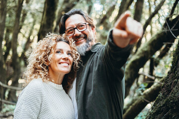 Happy couple of tourist admiring outdoor scenic place in nature forest with green trees and good environment concept. People enjoy together alternative weekend vacation and travel activity outdoors