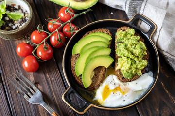 Wholemeal bread toast sliced avocado and poached egg on a rustic table. Healthy breakfast, sandwich with avocado and egg.