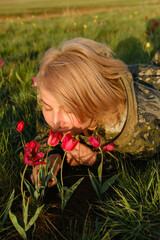 Naklejka premium Girl is smelling field tulips on hills. Travel, tourism, hiking.